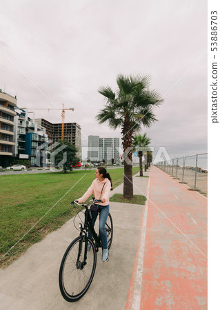 woman cyclist riding a bike on bike path woman cyclist riding a bike on bike path 53886703