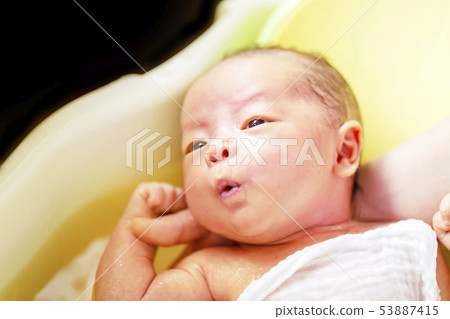 一個兩周大的嬰兒,浸泡在草藥湯劑浴中 一個兩周大的嬰兒,浸泡在草藥湯劑浴中 53887415