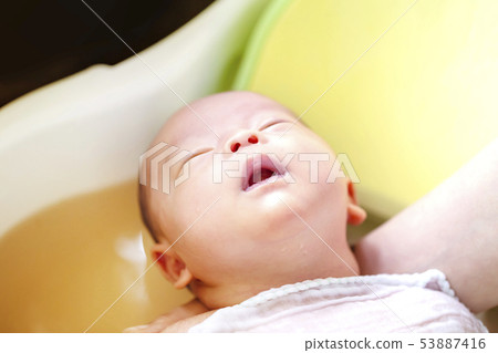 一個兩周大的嬰兒沐浴在帶有草藥湯劑的嬰兒浴中 53887416