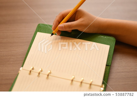 An orange ballpoint pen to write on a green cover system notebook. 1 53887782