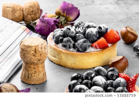 Blueberry and strawberry shortcake. There are hazelnuts, roses and wine corks on the table. Stone Blueberry and strawberry shortcake. There are hazelnuts, roses and wine corks on the table. Stone 53888759
