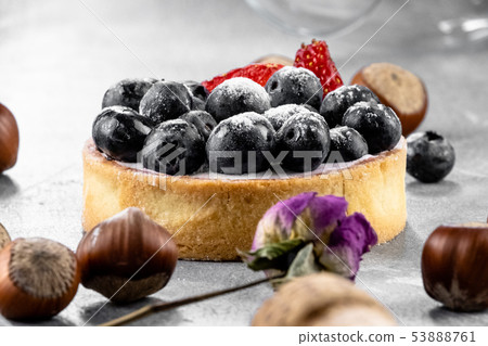 Blueberry and strawberry shortcake. There are hazelnuts, roses and wine corks on the table. Stone 53888761