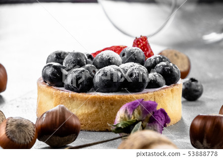 Blueberry and strawberry shortcake. There are hazelnuts, roses and wine corks on the table. Stone 53888778
