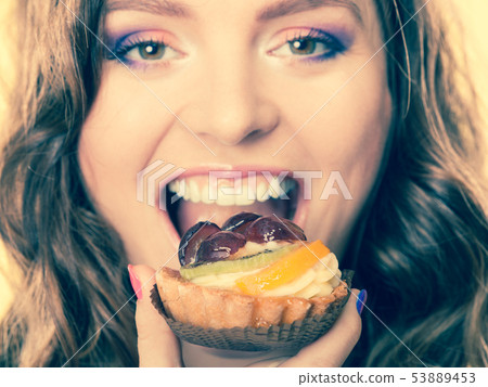 Closeup woman face and fruit cake Closeup woman face and fruit cake 53889453