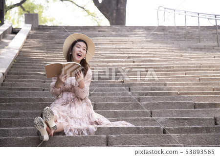 A woman sitting on the stairs and reading A woman sitting on the stairs and reading 53893565