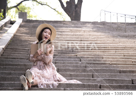 A woman sitting on the stairs and reading A woman sitting on the stairs and reading 53893566