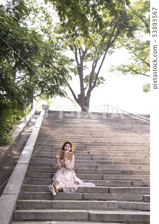 A woman sitting on the stairs and reading A woman sitting on the stairs and reading 53893567