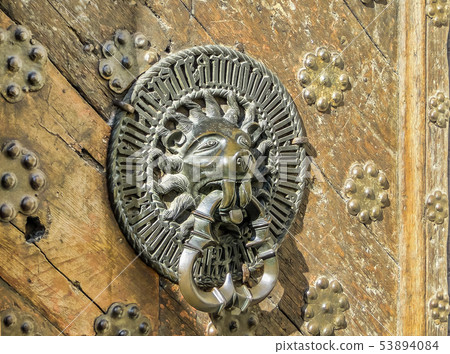 Carved door handle shaped as lion on old wooden Carved door handle shaped as lion on old wooden 53894084