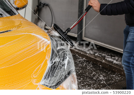Man cleaning his car in self serve carwash, brush 53900220