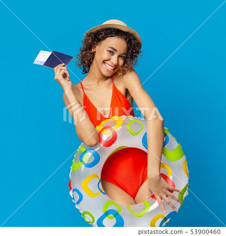 Cute african girl in swimwear holding tickets and inflatable ring 53900460