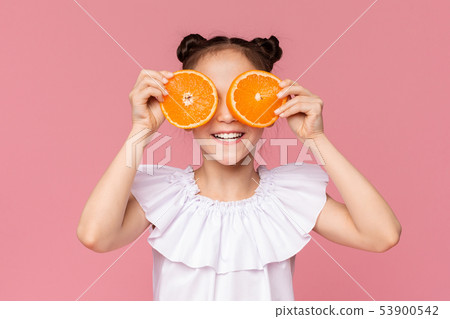 Little girl covering her eyes with fresh orange slices 53900542