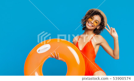 Happy african woman showing V sign with inflatable circle 53900574