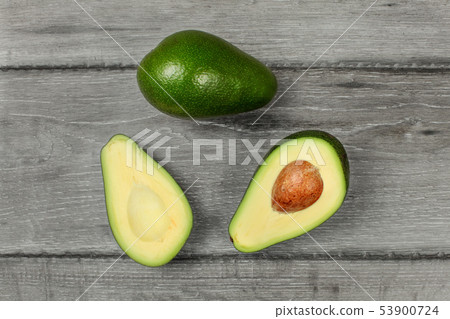 Table top view on avocado cut in half, with whole 53900724