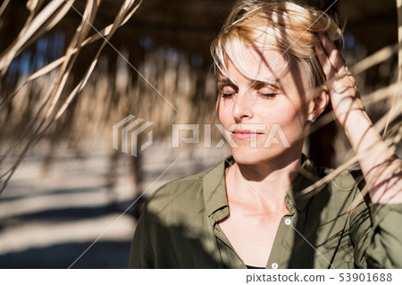 A young woman with closed eyes standing outdoors on beach. A young woman with closed eyes standing outdoors on beach. 53901688