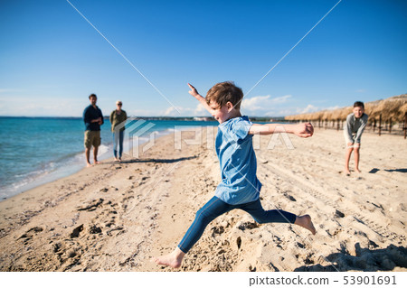 A small girl with family running outdoors on sand beach, having fun. A small girl with family running outdoors on sand beach, having fun. 53901691