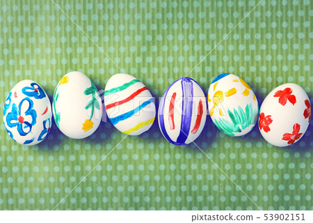 Painted Easter eggs on a green background with white polka dots 53902151