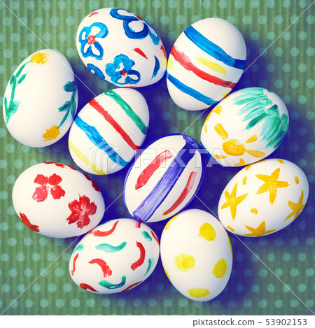 Painted Easter eggs on a green background with white polka dots Painted Easter eggs on a green background with white polka dots 53902153