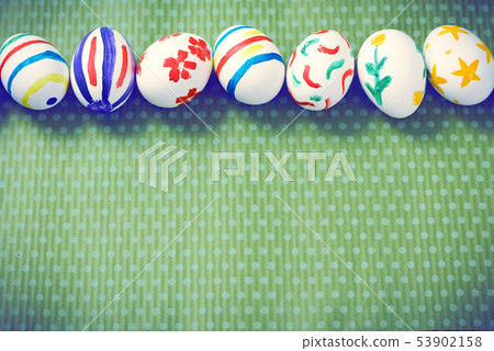 Painted Easter eggs on a green background with white polka dots Painted Easter eggs on a green background with white polka dots 53902158