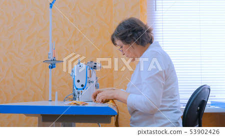 Woman designer sewing clothes with sewing machine at atelier Woman designer sewing clothes with sewing machine at atelier 53902426