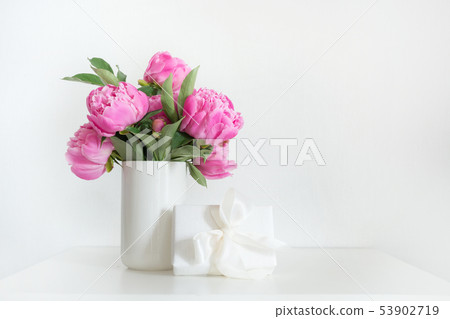 Bouquet of pink peony in vase with gift on white. Bouquet of pink peony in vase with gift on white. 53902719