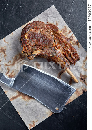Tomahawk steak with vegetables and a knife on the table. Grilled meat with grilled vegetables and Tomahawk steak with vegetables and a knife on the table. Grilled meat with grilled vegetables and 53903037