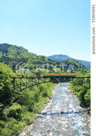 Train crossing the fresh green valley and the bridge 53904991