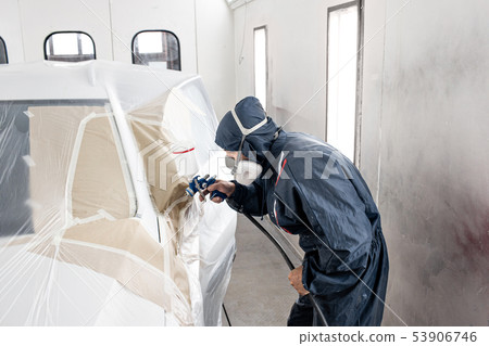 Car service station. Worker painting a white car in special garage, wearing costume and protective Car service station. Worker painting a white car in special garage, wearing costume and protective 53906746