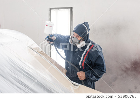 Car service station. Worker painting a white car in special garage, wearing costume and protective 53906763