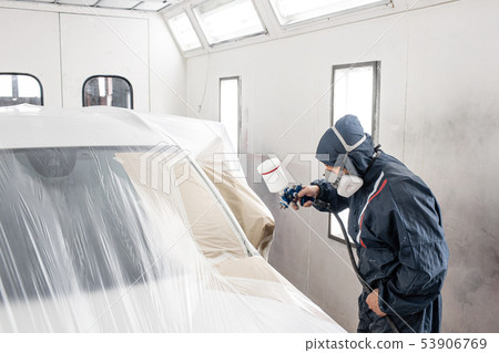 Car service station. Worker painting a white car in special garage, wearing costume and protective Car service station. Worker painting a white car in special garage, wearing costume and protective 53906769