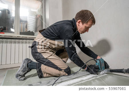 Worker is using a building tool, the milling tools and a vacuum cleaner. drywall at ninety degrees. 53907081