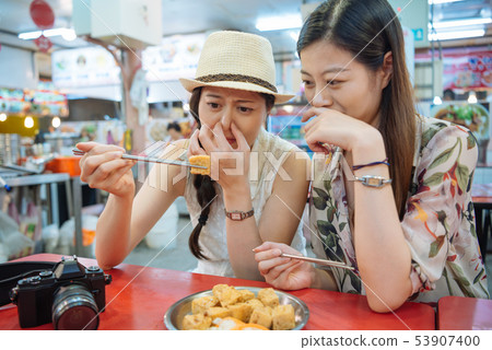 foreigner female travelers trying stinky tofu foreigner female travelers trying stinky tofu 53907400