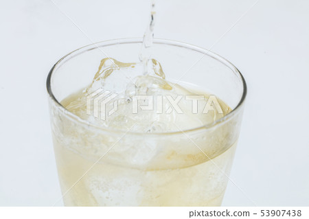 Pouring highball into glass on white background Pouring highball into glass on white background 53907438