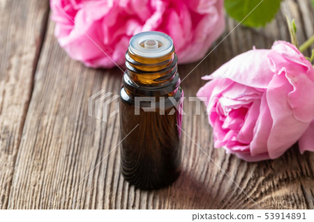 A bottle of rose essential oil with rose flowers A bottle of rose essential oil with rose flowers 53914891