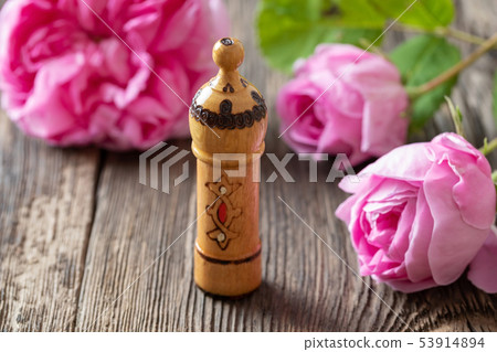 A bottle of rose essential oil with rose flowers A bottle of rose essential oil with rose flowers 53914894