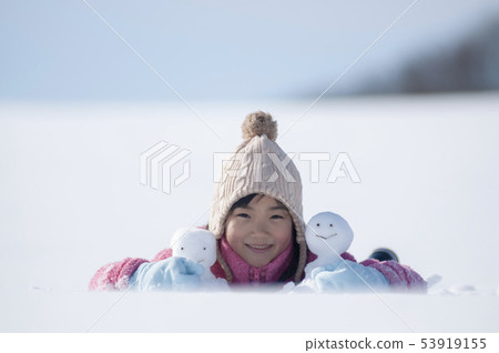 Smiling girl with a snowman in a snowy field Smiling girl with a snowman in a snowy field 53919155