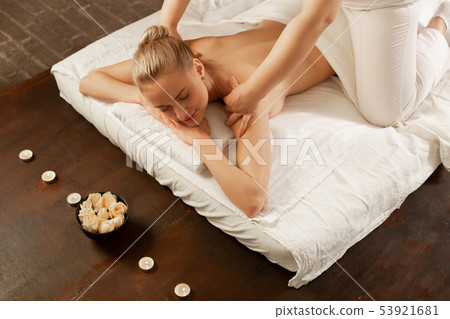 Calm young woman with blonde hair bun going through massage session 53921681