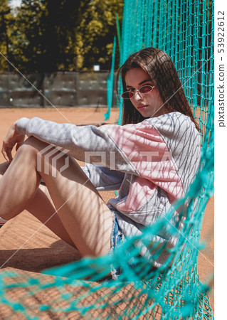 Stylish modern woman poses for a photo on a sports ground in the summer Stylish modern woman poses for a photo on a sports ground in the summer 53922612