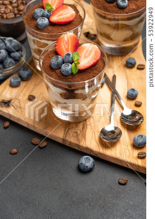 Classic tiramisu dessert with blueberries and strawberries in a glass on dark concrete background Classic tiramisu dessert with blueberries and strawberries in a glass on dark concrete background 53922949
