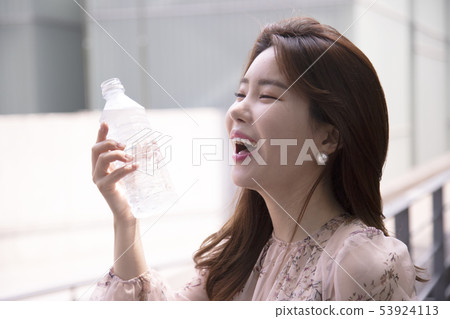 A woman smiling with a drinking water bottle 53924113