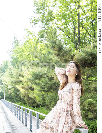 Young female model standing on stairs with forest background and looking at sky Young female model standing on stairs with forest background and looking at sky 53926396