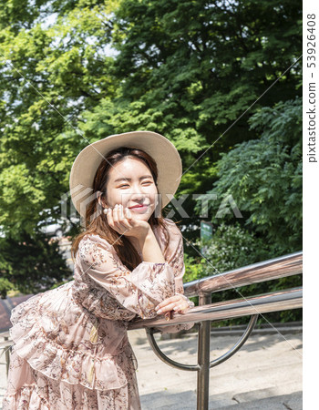 Young female model standing on stairs with forest background and smiling Young female model standing on stairs with forest background and smiling 53926408