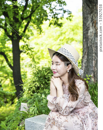 A young female model sitting in the forest in Namsan, Seoul, holding both hands on her chin A young female model sitting in the forest in Namsan, Seoul, holding both hands on her chin 53927038
