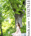A young female model sitting under a zelkova in the forest of Namsan Park in Seoul 53927618