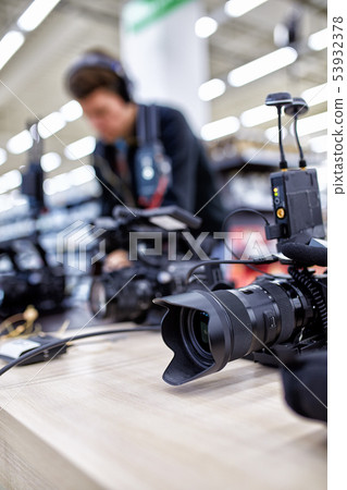 Videographer shooting a film or a television program in a studio with a professional camera Videographer shooting a film or a television program in a studio with a professional camera 53932378