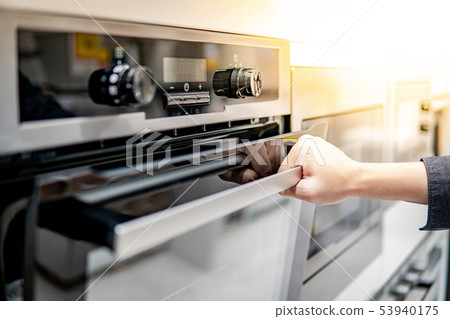 Male hand opening oven door Male hand opening oven door 53940175