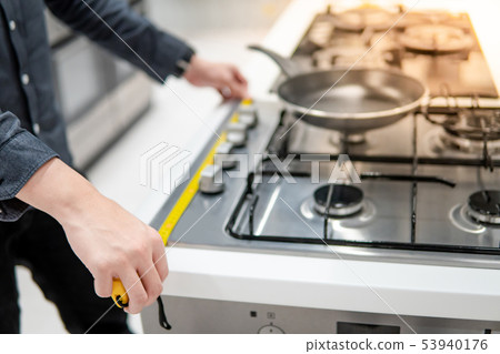 Male hand using tape measure on gas stove Male hand using tape measure on gas stove 53940176