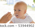 Mother or father feeding cute baby boy with cream 53944902