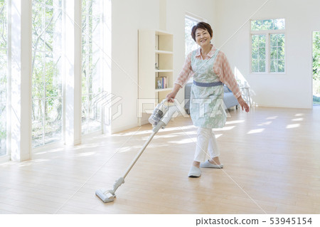Smiling senior lady vacuuming on the floor 53945154