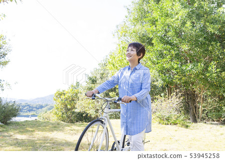 Senior woman pushing a bike and taking a walk 53945258