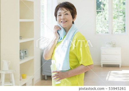 Smiling senior woman wiping face with towel 53945261